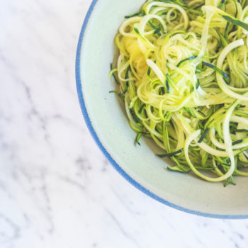 Zucchini spaghetti or noodles (zoodles) in a bowl with marble background Top view overhead