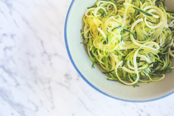 Zucchini spaghetti or noodles (zoodles) in a bowl with marble background Top view overhead