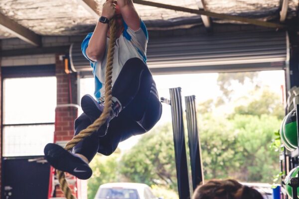 anny climbing a rope almost at the roof locking her feet in 
